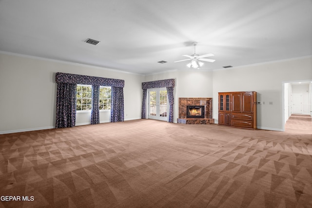 unfurnished living room with a premium fireplace, ceiling fan, crown molding, and light colored carpet