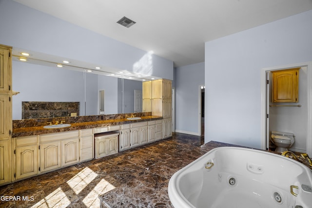 bathroom with toilet, a tub to relax in, and vanity