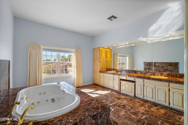 bathroom featuring a wealth of natural light, vanity, and tiled tub