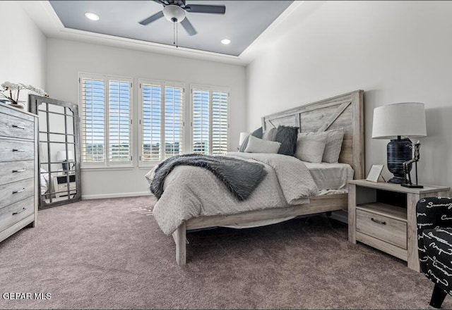 bedroom featuring carpet, ceiling fan, a raised ceiling, and multiple windows