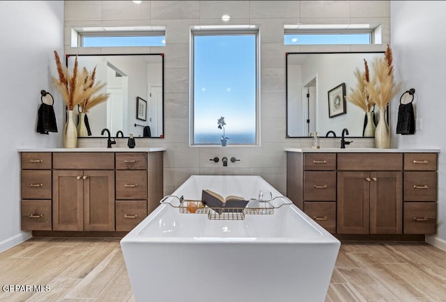 bathroom with a bath, plenty of natural light, and tile walls