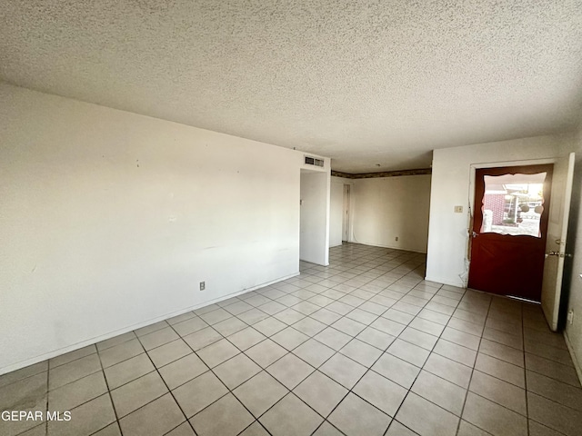 tiled empty room featuring a textured ceiling