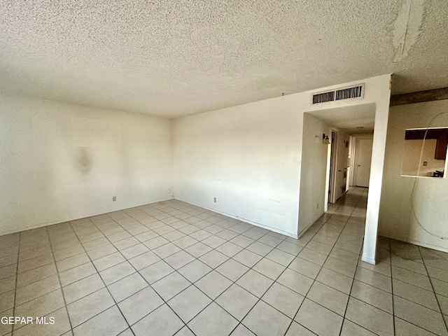 tiled empty room with a textured ceiling