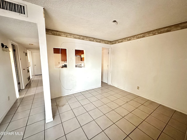 spare room with light tile patterned flooring and a textured ceiling