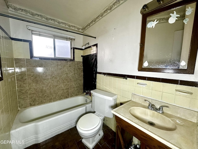 full bathroom with tile walls, vanity, tiled shower / bath, and toilet