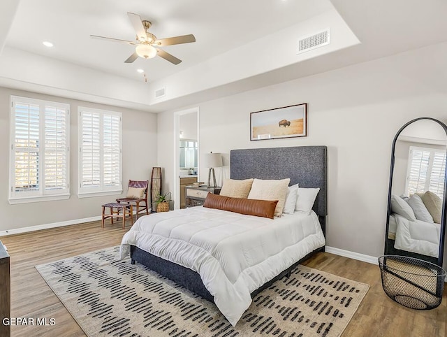 bedroom featuring hardwood / wood-style flooring, ensuite bath, and ceiling fan