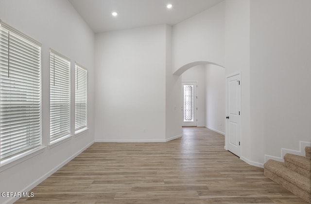 spare room with a towering ceiling and light wood-type flooring