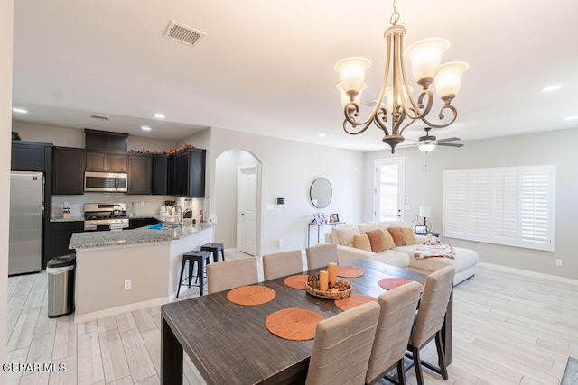 dining room with sink, ceiling fan with notable chandelier, and light wood-type flooring