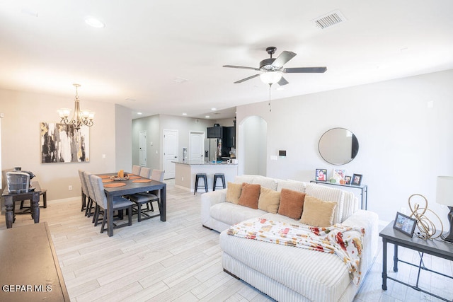 living room with light hardwood / wood-style floors and ceiling fan with notable chandelier