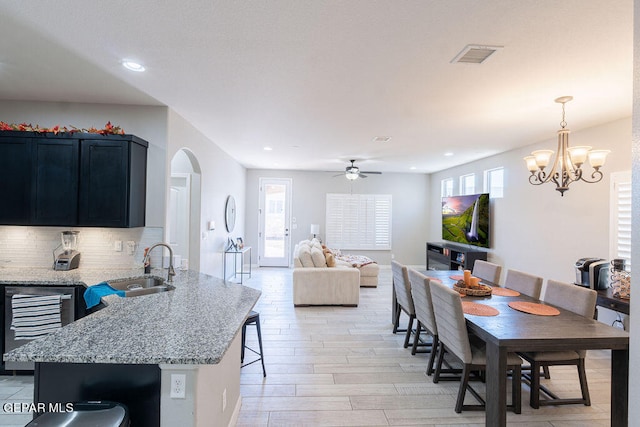 dining room with light hardwood / wood-style floors, sink, beverage cooler, and ceiling fan with notable chandelier