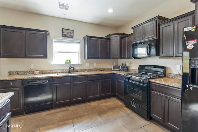 kitchen with light stone counters, black appliances, sink, and dark brown cabinets
