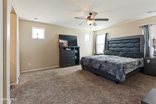 carpeted bedroom with a textured ceiling, multiple windows, and ceiling fan