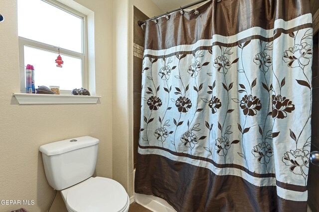 bathroom with toilet and a shower with shower curtain