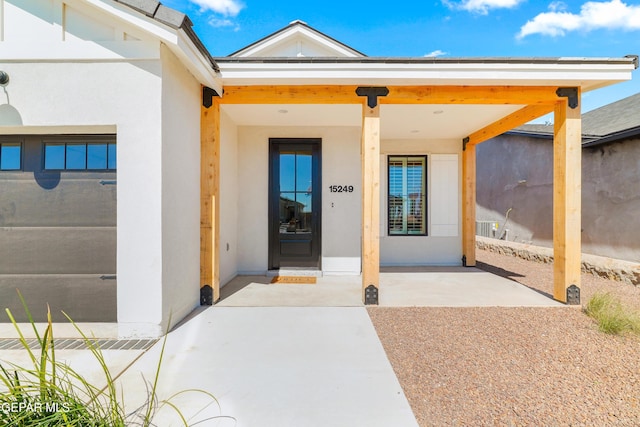 view of exterior entry featuring covered porch and stucco siding