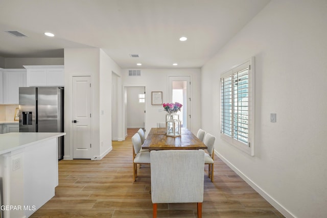 dining space featuring light wood finished floors, baseboards, visible vents, and recessed lighting