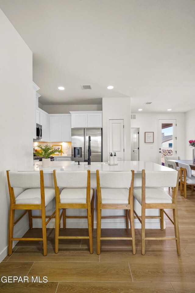 dining area with light wood finished floors, visible vents, and recessed lighting