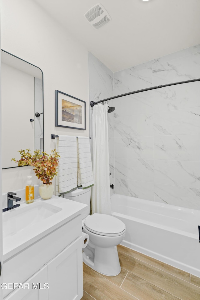 bathroom featuring wood finished floors, vanity, shower / tub combo with curtain, toilet, and visible vents