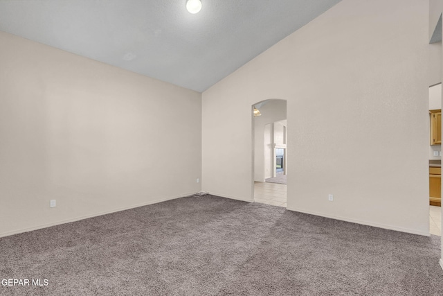 spare room featuring high vaulted ceiling and light colored carpet