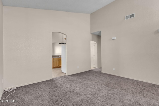 carpeted empty room with a towering ceiling