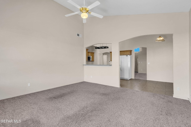 unfurnished living room featuring high vaulted ceiling, ceiling fan, and dark carpet