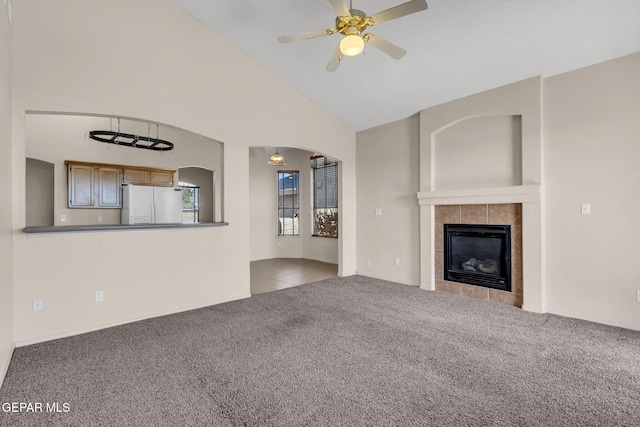 unfurnished living room featuring high vaulted ceiling, light colored carpet, ceiling fan, and a tile fireplace