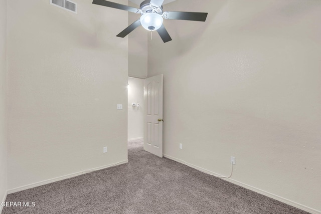 unfurnished room featuring a towering ceiling, ceiling fan, and carpet