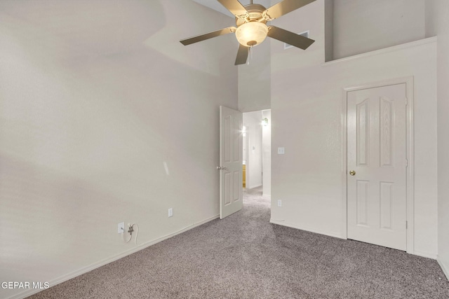 unfurnished bedroom with carpet flooring, ceiling fan, and a high ceiling