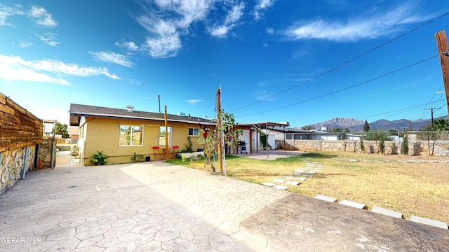 rear view of property featuring a mountain view, a yard, and a patio