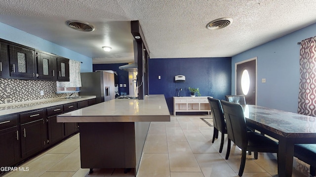 kitchen featuring a textured ceiling, a center island, and stainless steel refrigerator with ice dispenser