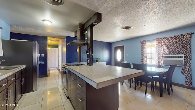 kitchen featuring a kitchen island, dark brown cabinetry, a textured ceiling, and appliances with stainless steel finishes