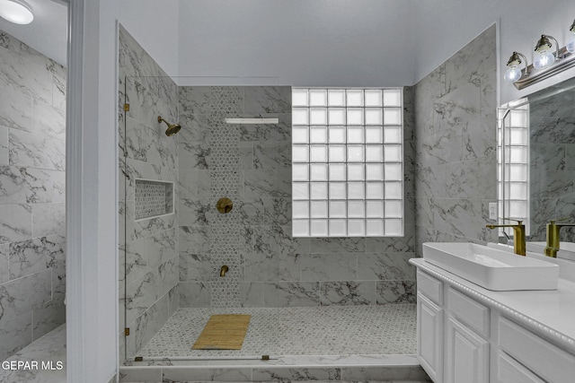 bathroom featuring vanity, a healthy amount of sunlight, and tiled shower