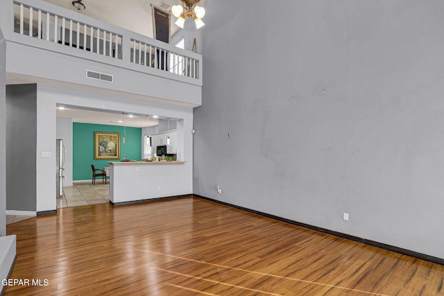 unfurnished living room with a towering ceiling and light wood-type flooring