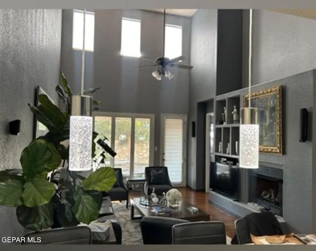 living room featuring hardwood / wood-style flooring, plenty of natural light, ceiling fan, and a towering ceiling