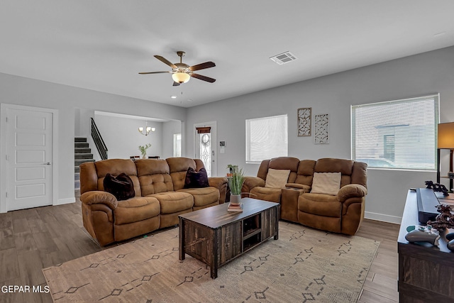 living room featuring ceiling fan with notable chandelier and light hardwood / wood-style floors