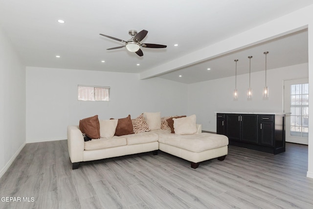 living room featuring beamed ceiling, light wood-type flooring, and ceiling fan