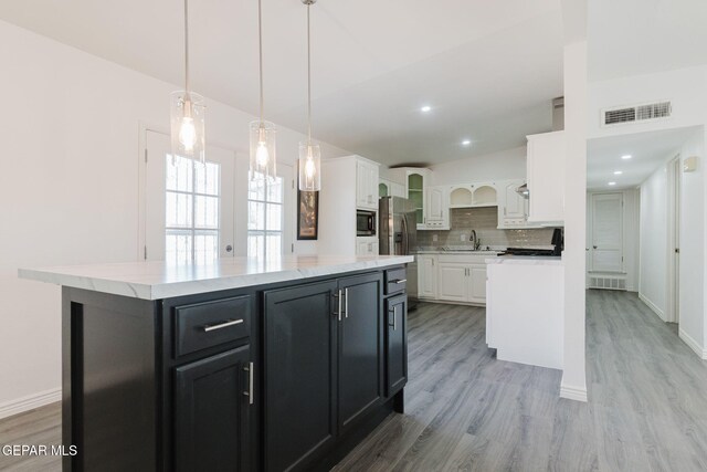 kitchen featuring white cabinets, sink, light hardwood / wood-style floors, decorative light fixtures, and a center island