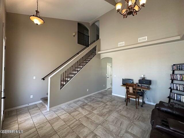 12419 Winners Cir, El Paso, TX 79928 - living room featuring stairs, arched walkways, a desk, a chandelier, and a high ceiling