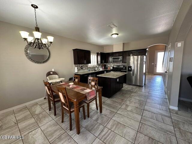 12419 Winners Cir, El Paso, TX 79928 - dining room featuring arched walkways, a chandelier, light marble finish flooring, and baseboards