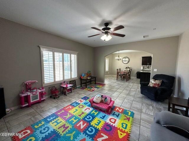 recreation room featuring ceiling fan with notable chandelier