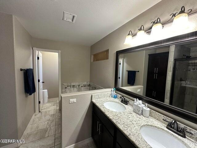 12419 Winners Cir, El Paso, TX 79928 - bathroom with marble look tiles, a stall shower, double vanity, and baseboards