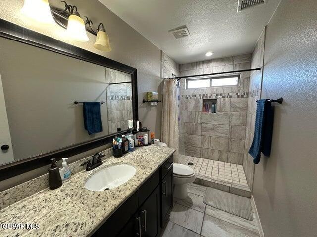 bathroom with toilet, a textured ceiling, a shower with curtain, and vanity