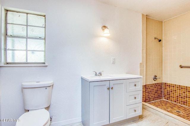 bathroom with toilet, vanity, and a tile shower