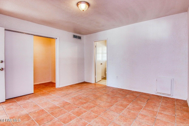 empty room with a textured ceiling and light tile patterned floors