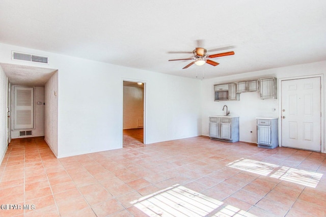 unfurnished living room with sink, ceiling fan, and light tile patterned floors