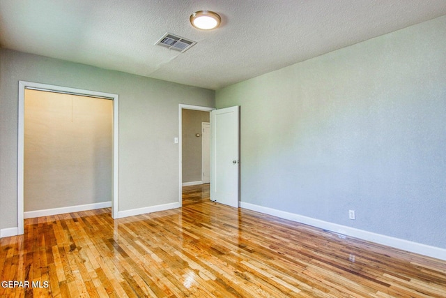 unfurnished bedroom featuring a closet, a textured ceiling, and light wood-type flooring