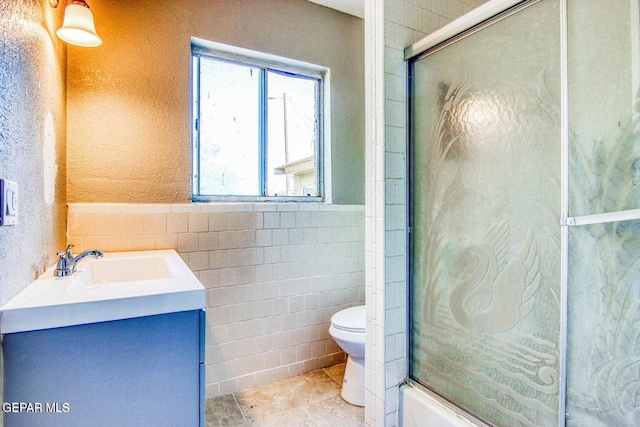 bathroom with vanity, toilet, tile walls, and an enclosed shower