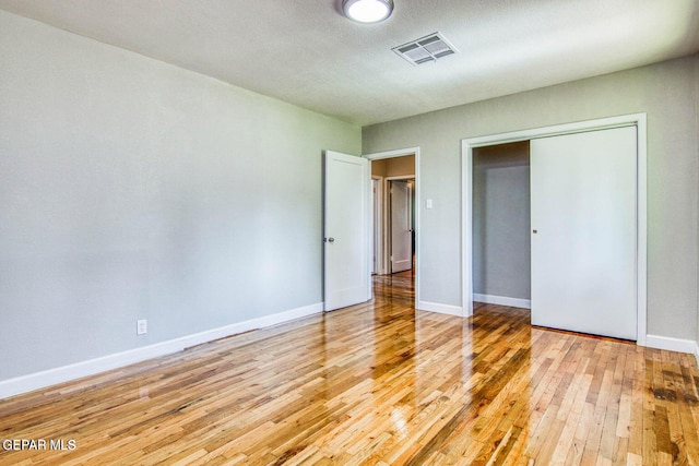 unfurnished bedroom with light hardwood / wood-style flooring, a textured ceiling, and a closet