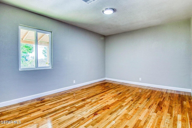 spare room with a textured ceiling and light hardwood / wood-style floors