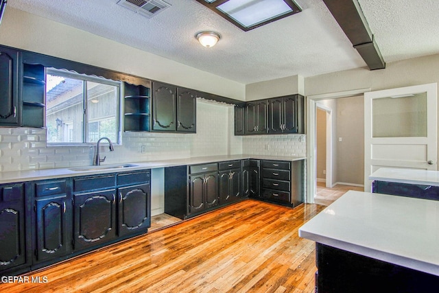 kitchen featuring light hardwood / wood-style flooring, a textured ceiling, sink, and backsplash