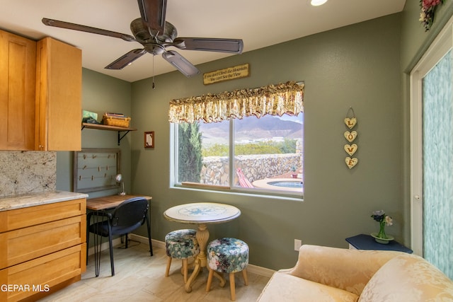 living area with built in desk, a mountain view, and ceiling fan